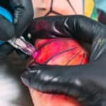 tatuatrice che effettua un tatuaggio realistico su cliente